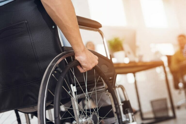 A disabled man is sitting in a wheelchair. He holds his hands on the wheel. Concept for What Is an Impairment Rating in a Virginia Workers’ Compensation Case?
