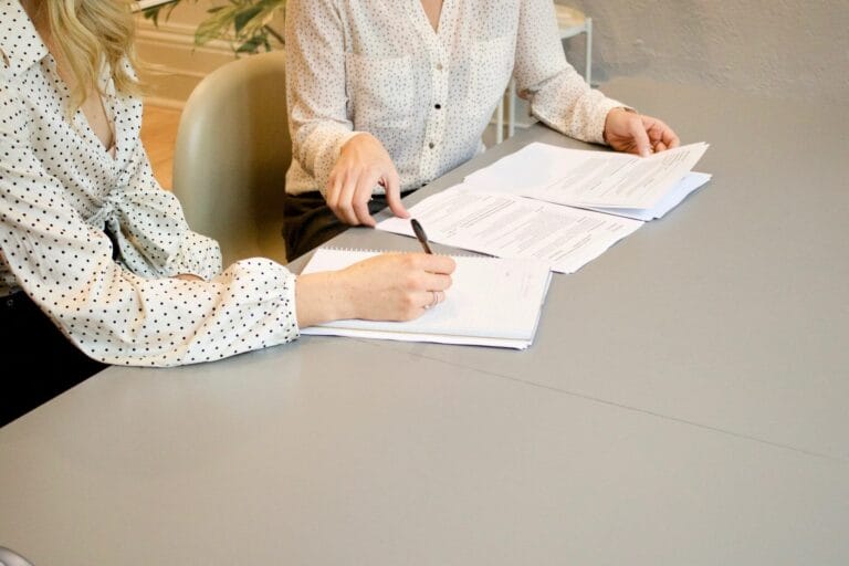 An employee and employer sitting down to report a workplace accident and filling out paperwork.