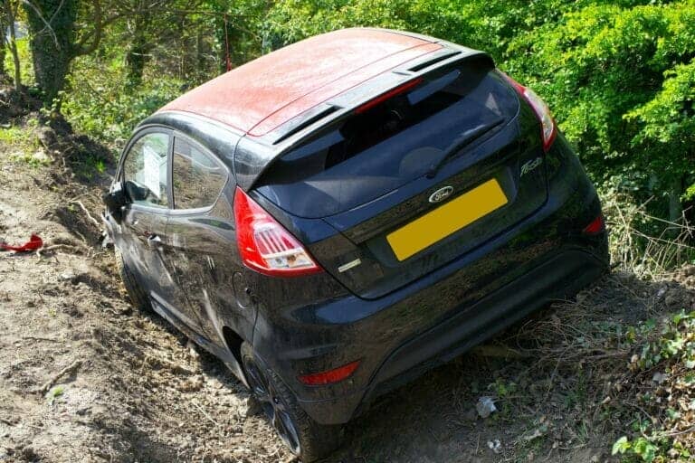 A car that has crashed into a ditch and the driver sitting in the car wondering what will happen to their body after the accident.