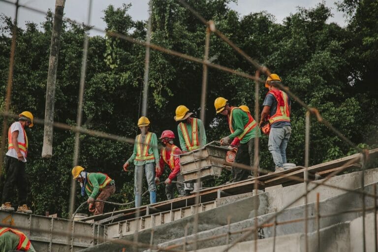 Several construction workers carrying cement along the side of a building on a job site in one of the jobs that has one of the highest injury rates.