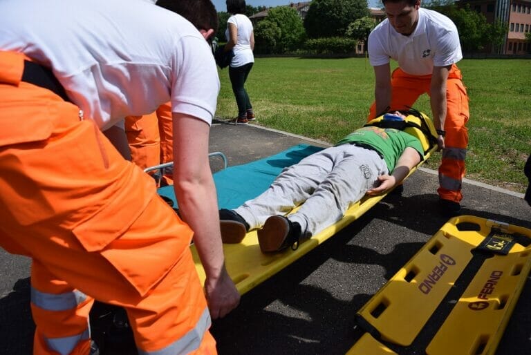 man being carried by two other men on stretcher