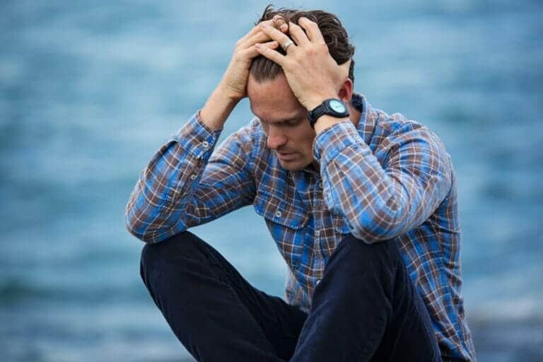 man sitting down with hands on his head in emotional distress after an accident