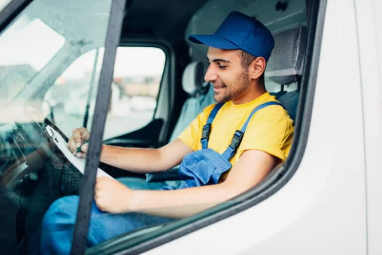 male truck driver in uniform sitting in cab of truck