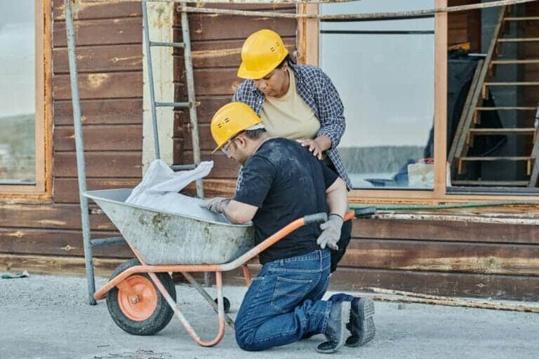 A construction worker on his knees holding his back after a back injury at work