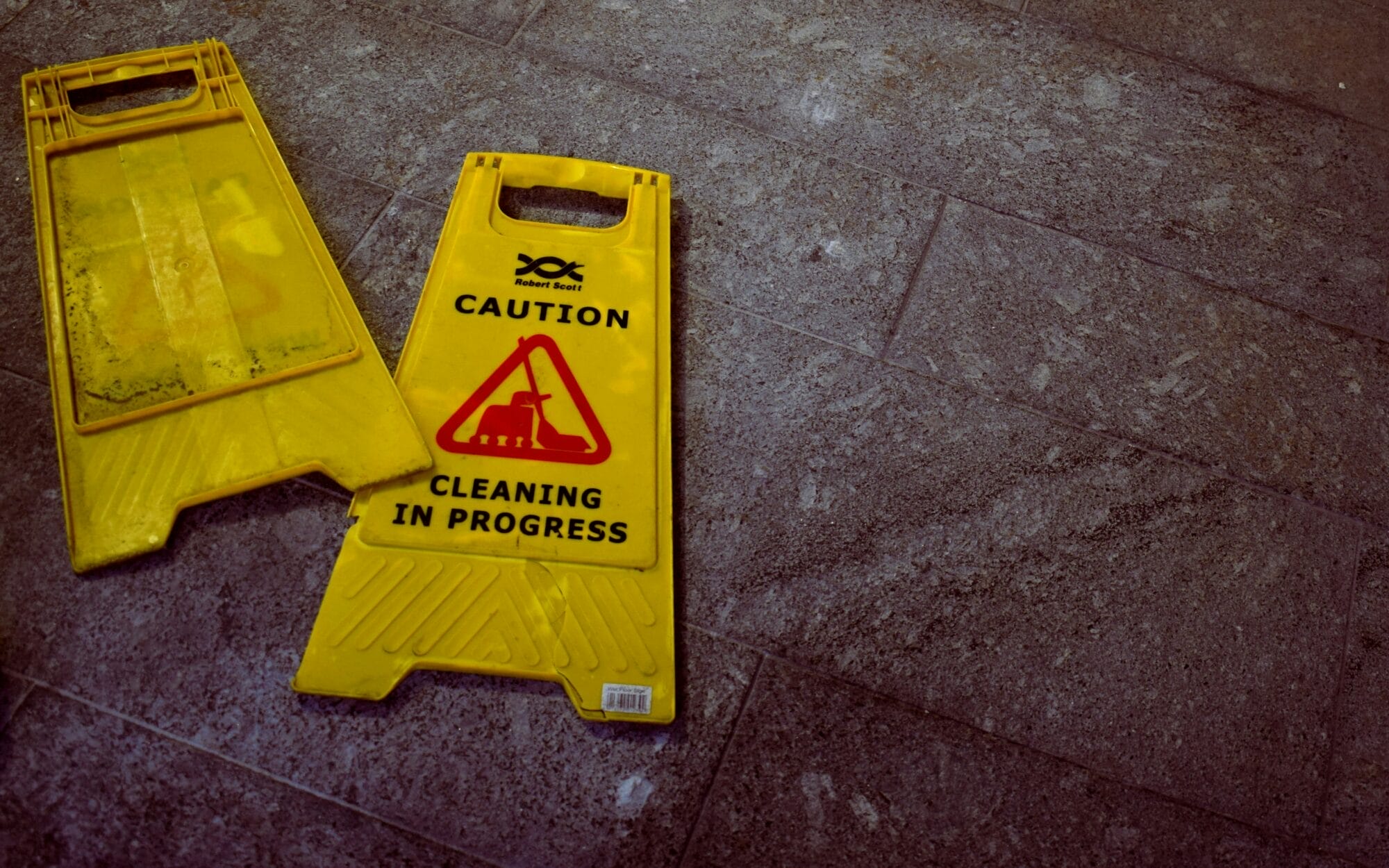 2 Caution cleaning in progress signs laying on the floor