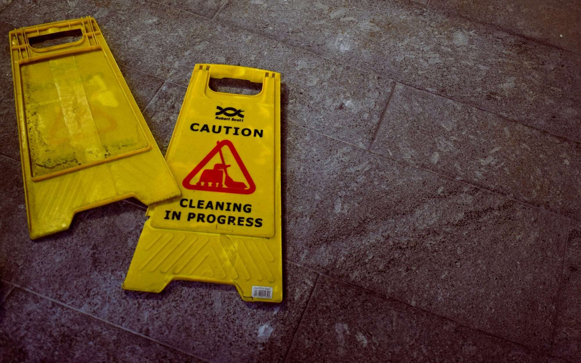 2 Caution cleaning in progress signs laying on the floor