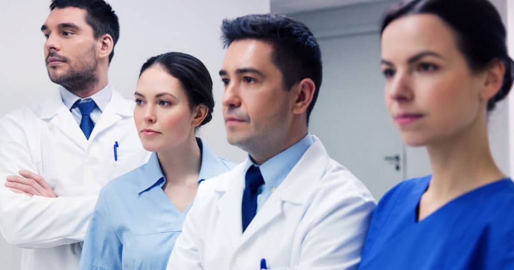 A group of doctors and medical staff standing together in a hospital, looking focused and professional.