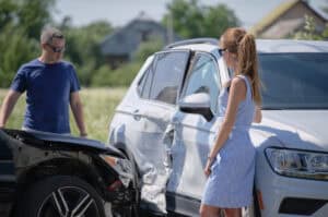 Black car and White SUV in accident with male and female drivers discussing outside.