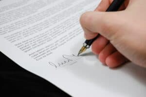 Close-up of a person signing a legal document with a fountain pen, symbolizing the formal execution of a prenuptial agreement.