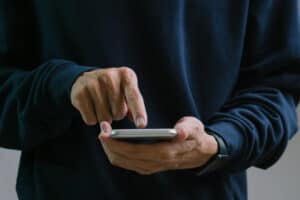 Person using a smartphone, illustrating how social media activity can impact a workers’ compensation claim and be reviewed by insurance investigators