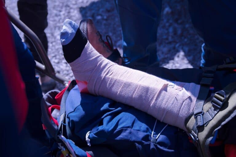 Rescue workers assist an injured person with a bandaged leg after an accident, illustrating how accident injuries can worsen a pre-existing condition and require immediate medical attention.